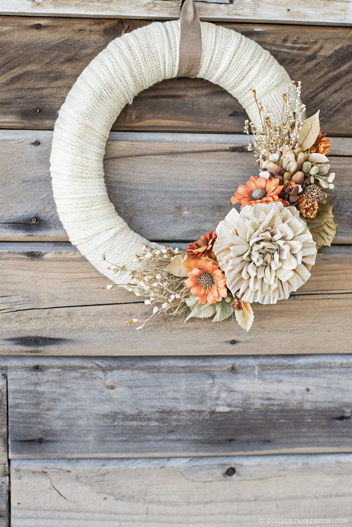 Rustic yarn-wrapped wreath adorned with orange and beige flowers, perfect for cozy fall home decor