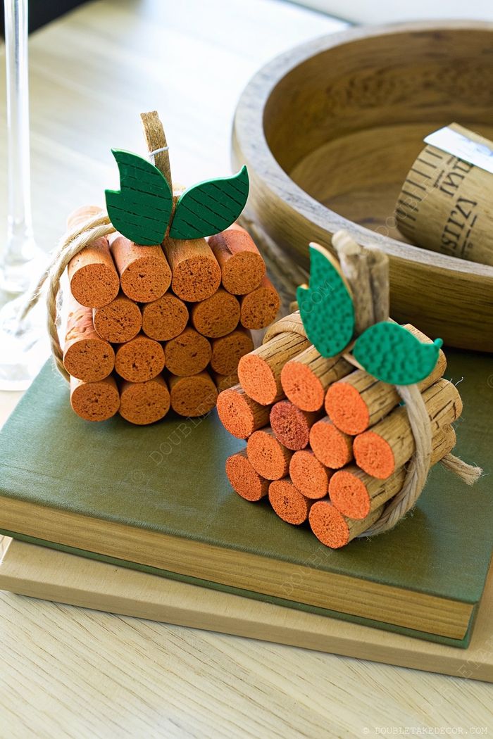 Decorative fall pumpkins made from painted orange craft sticks with green leaves, arranged with stacked books for a cozy autumn centerpiece.
