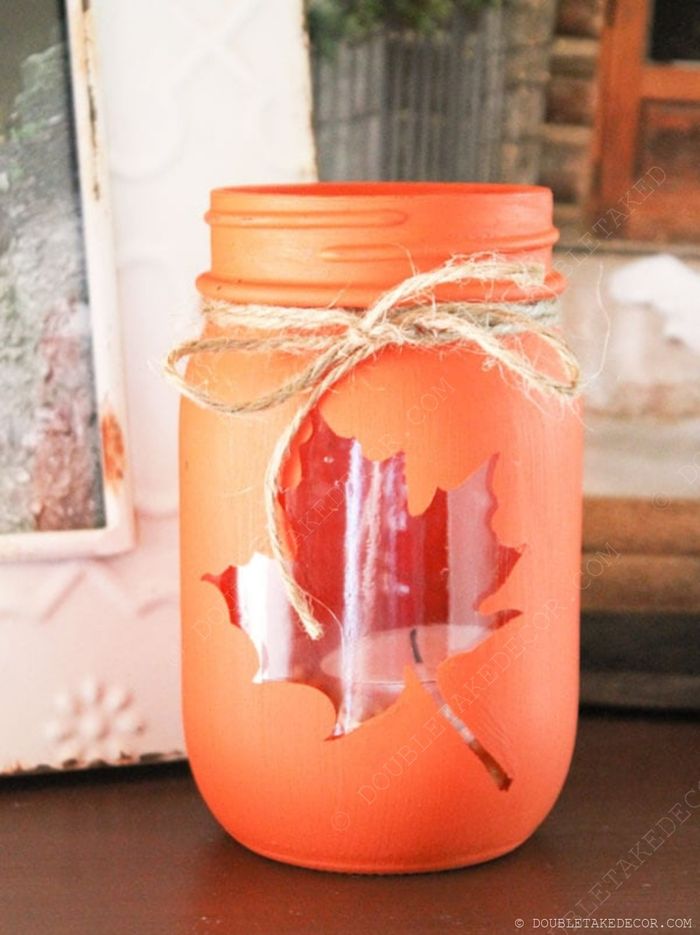 Fall-themed orange mason jar with maple leaf cutout, decorated with twine bow, perfect for autumn home decor