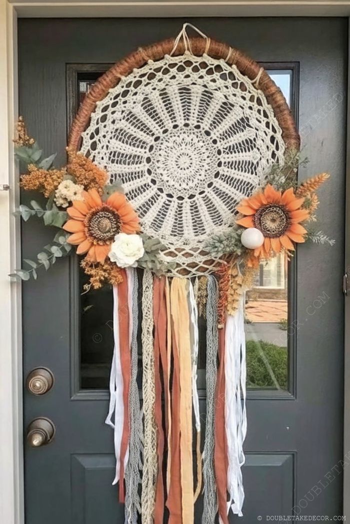 Intricate cream lace dreamcatcher with sunflowers and fall foliage hanging on a green door with flowing fabric streamers in autumn colors