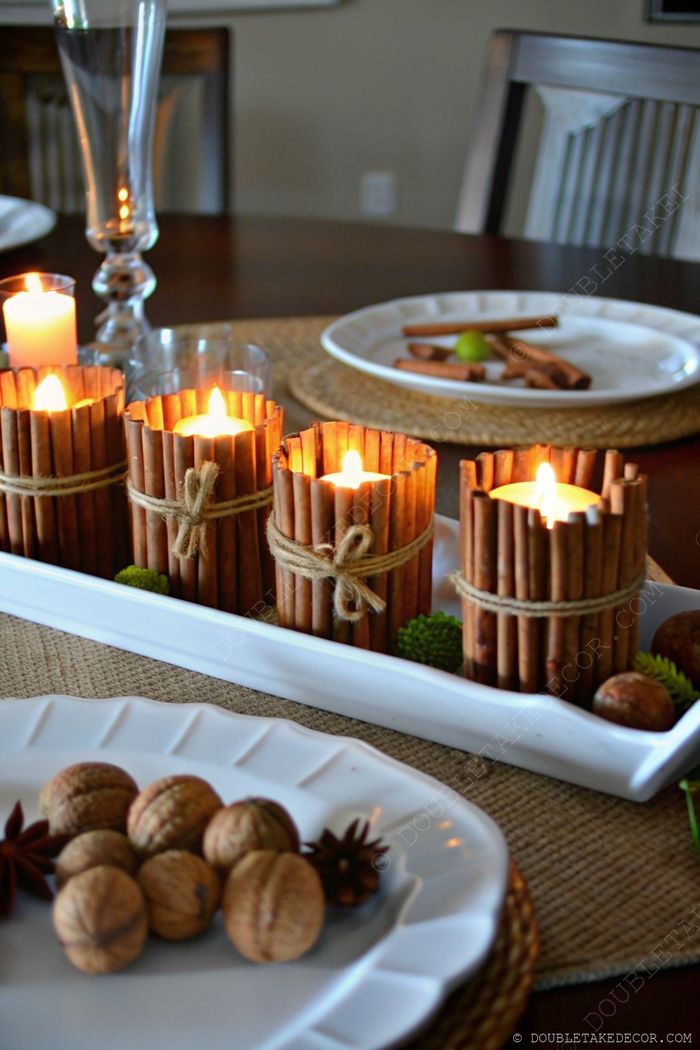 Elegant fall centerpiece with cinnamon-wrapped candles on a white tray, adorned with greenery and natural elements for rustic charm.