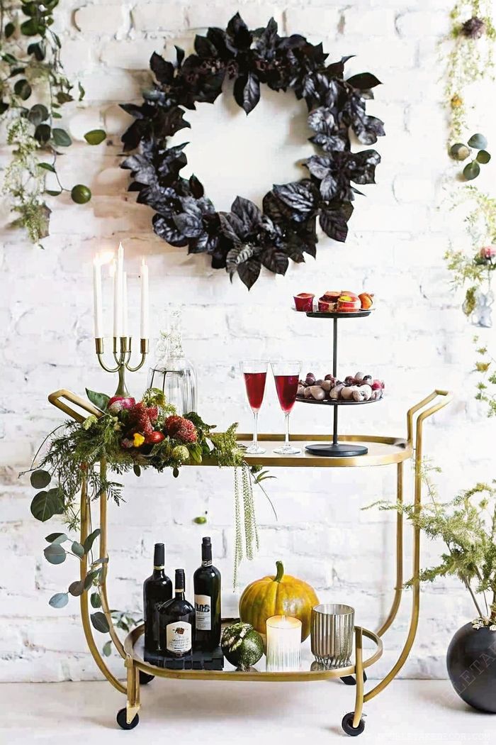 Festive Halloween bar cart with gold metal frame, decorated with pumpkins, gourds, and spooky elegant drinks for seasonal entertaining.